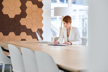 Businesswoman working on paperwork in modern office boardroom