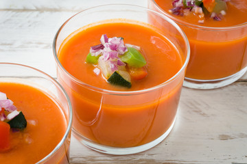 Gazpacho soup and ingredients on white wooden background
