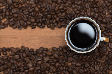 Кофейные зерна и кружка горячего напитка на деревянном фоне 