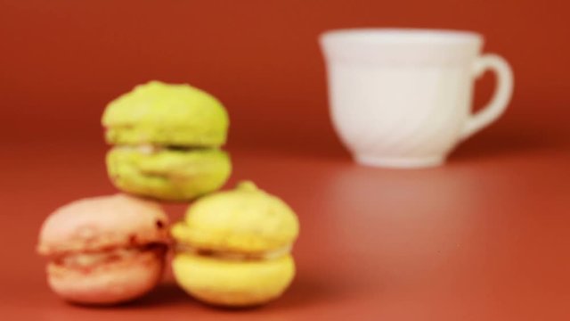 Cup of coffee with macaroons on a brown background.