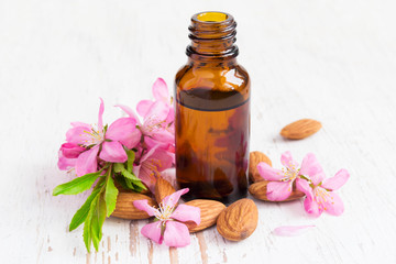 Fototapeta na wymiar small bottle of almond oil, almonds and flowers