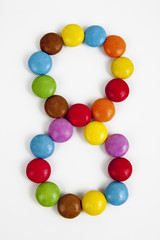 Il numero otto formato da coloratissimi confetti di cioccolato.