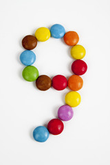Il numero nove formato da coloratissimi confetti di cioccolato.