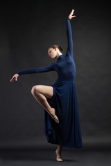 Posing dancer in blue dress over dark background