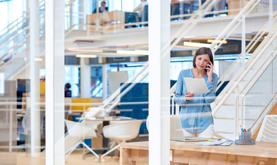 Fototapeta premium Businesswoman in open-plan office talking on phone