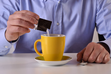 Colocando sobre de azucar a la tasa de cafe.