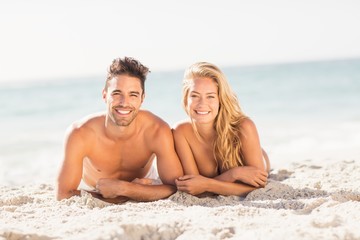 Fototapeta premium Young couple lying on sand