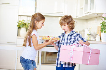 Zwei Kinder am Muttertag mit Geschenk und Kuchen