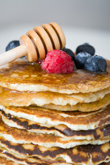 American breakfast. Pancakes with blueberries, raspberries and honey
