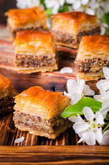 Walnut baklava on wooden vintage background with spring flowers. Arabic cuisine. Selective focus