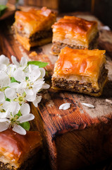 Traditional arabic sweets walnuts baklava on wooden vintage background with springs flowers. Selective focus. 