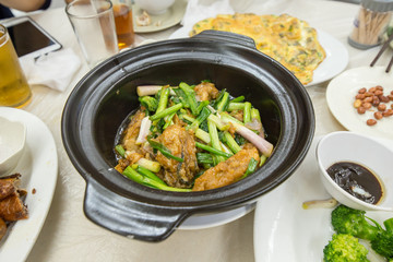 A large black bowl with fried oysters and vegetables in soup