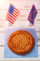 Table flags beside round pie. Flag of Europe and USA. Let's share our values. Make peace and eat dessert.