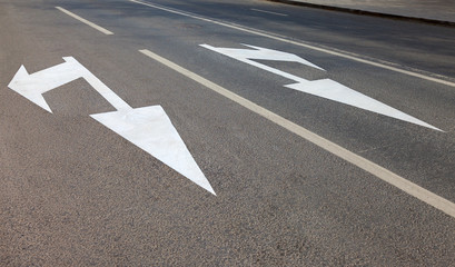 Road with white marking lines and direction of motion on asphalt