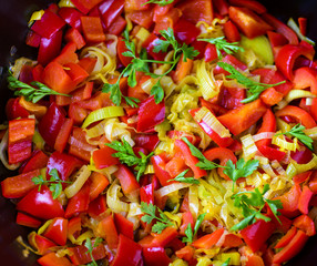 Mixed fresh vegetables (pepper, leek, herbs) in a skillet