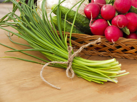 Spring vegetables in basket: radish, cucumber, chives and cauliflower
