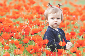 Funny child holding a balloon outdoor at poppy field