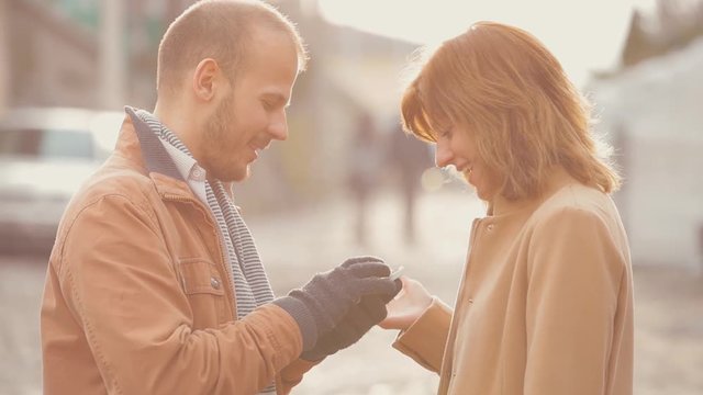 Couple having a good time outdoors with a cellphone.