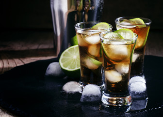 Fototapeta premium Alcoholic cocktail spiced rum with cola, lime and ice cubes, sha