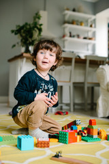 Fototapeta premium Little boy playing in the constructor on the floor of the house.