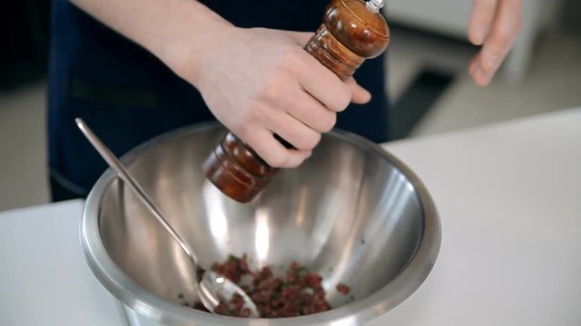 A chef is adding salt and pepper