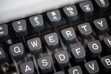 Detail view of the keys on a portable metal typewriter, circa 1970, on the diagonal.  Focus is on QWERTY.  May be used to symbolize journalism or creativity or an antiquated method of communication.
