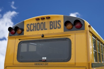 BACK OF A SCHOOL BUS WITH BRIGHT BLUE SKY BACKGROUND
