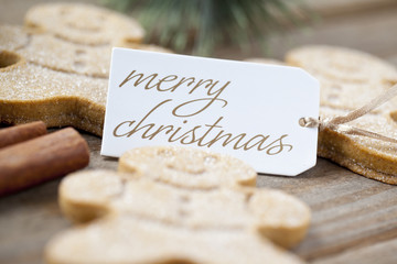 defocused image of gingerbread candies with merry christmas tag.