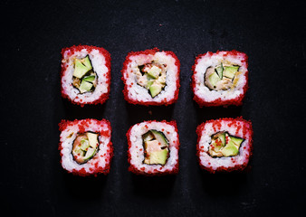 Philadelphia Roll with caviar, top view, a dark stone background