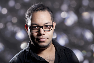 Mann mit afrikanischer Flechtfrisur und Brille im Glitzerlicht Porträt