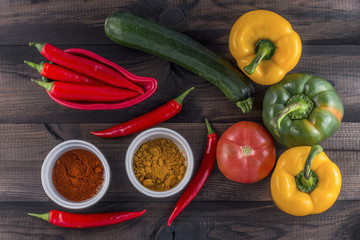 green and yellow paprika with tomato, zucchini and chilli powder on wooden background