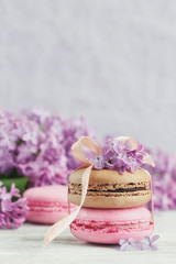Cup of black coffee, lilac flowers and sweet pastel french macar