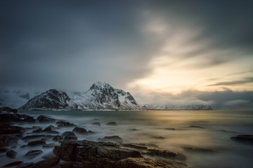 Sunset on rocky coast near Flakstad with mountains on background, Lofoten 