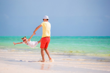 Happy father and his adorable little daughter at tropical beach having fun