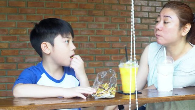 Happy asian mom with her son eating snack and playing together make fun