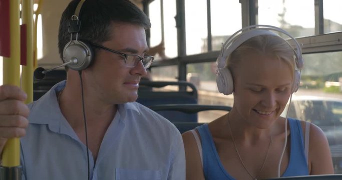 Young man and woman listening to music in headphones during bus ride. Commuting in the city