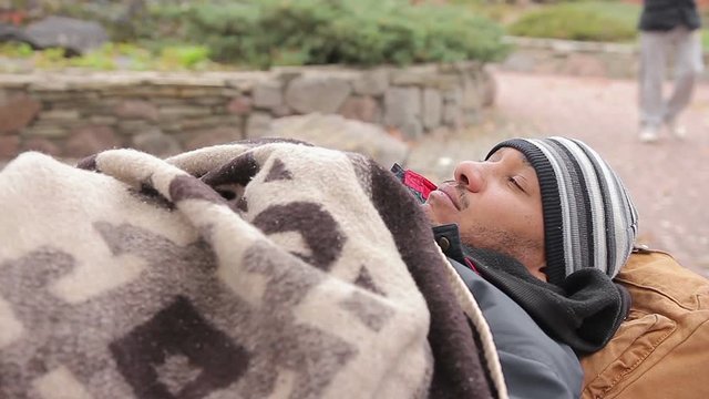 Unhappy homeless man sleeping in city street, socially vulnerable poor person