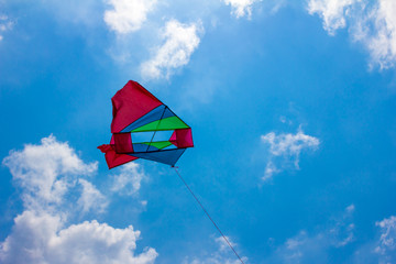 Colourful red, green Kite flying in the blue sky with toned colour and selective focus