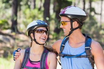 Fototapeta na wymiar Happy young couple wearing helmets at forest