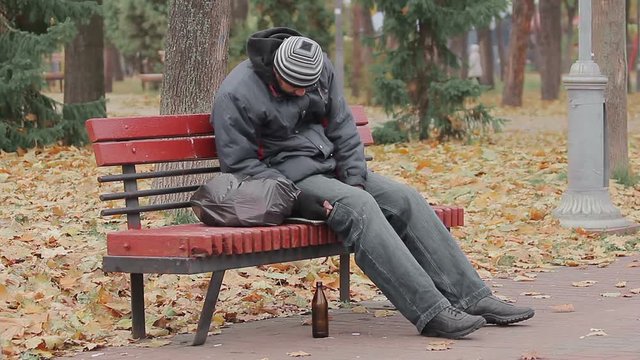 Disgusting drunk man sleeping and coughing on bench in city park, alcohol addict