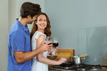 Young couple holding wine glass in kitchen 