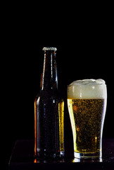 Bottles of beer and glass getting cool on black  background