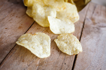 Opened pack of delicious potato chips on wood table