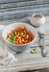 Fresh carrot and chickpea salad on a light wooden background. Healthy vegetarian food