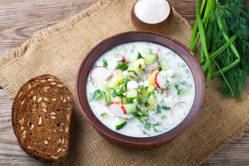 Okroshka on kefir with rye bread on a wooden table