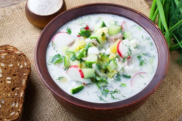 Okroshka on kefir with rye bread on a wooden table