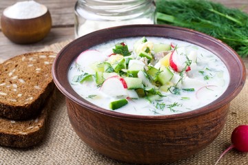 Okroshka on kefir with rye bread on a wooden table