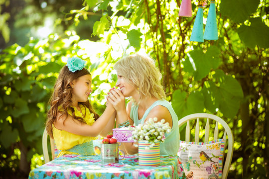 A mather and a dother hold hends and look to eash other in the garden