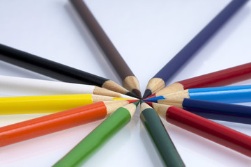 Colored pencils arranged with points all facing in creating a circle shot from a low angle, center of focus on tips of pencils