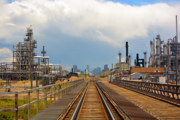Obraz premium Oil and Gas Refinery Distillation Towers with Railroad Tracks and a Distant City